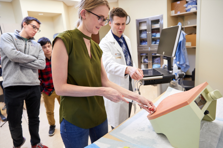Matt Freer, MD, explains a paracentesis procedure to fourth-year medical students in the capstone course at the Howard and Joyce Wood Simulation Center in the Farrell Learning and Teaching Center. MATT MILLER/WASHU MEDICINE